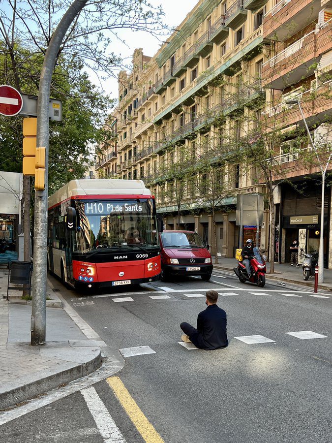 Un joven pierde el autobús y se sienta en medio de la calle para impedir su paso como protesta en Barcelona